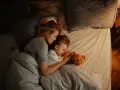 Mutter und Kind schlafen eng umschlungen. Ab wann Babys bewusst kuscheln, zeigt diese Szene der Geborgenheit.