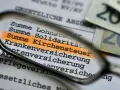 Durch eine Lupe wird die "Summe Kirchensteuer" auf einem Dokument hervorgehoben. Dies zeigt, wo Kirchensteuer anfällt.
