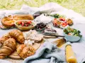Pyszne jedzenie na piknik: świeże pieczywo, owoce, sałatka, sery i napoje.