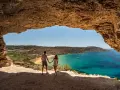 Para w jaskini podziwia widok na turkusowe morze i plażę. Malta pogoda wrzesień idealna na wakacje.
