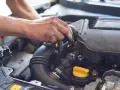 Mechanik pracuje przy silniku, regulując układ dolotowy.