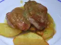 Solomillo jugoso con salsa de whisky sobre patatas gajo en un plato blanco.
