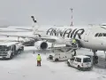 Samolot Finnair na lotnisku w śnieżny dzień. Pracownicy obsługi naziemnej przygotowują samolot do lotu. Czy do Finlandii można lecieć na dowód?