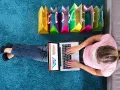 Kobieta robi zakupy online, obok kolorowe torby. To idealny sposób na zakupy z **Deezee firma**.