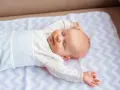 Śpiące niemowlę na kolorowej macie. Średnio główka niemowlaka rośnie ok. 1-2 cm miesięcznie.