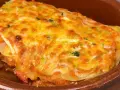 Deliciosa lasaña de atún gratinada con queso dorado y hierbas frescas, servida en una cazuela de barro.