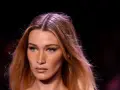 Primo piano di una modella con capelli biondi mossi e occhi verdi penetranti. La sua espressione è enigmatica, quasi a chiedersi chi è la donna più bella del mondo.
