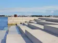 Kamienne schody nad morzem, z widokiem na miasto w oddali. Zadar co warto zobaczyć - idealne miejsce na spacer.