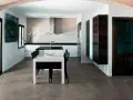 Modern kitchen with a dining area. The **pavimento in cemento per interni costi** is visible, offering a sleek and contemporary look.
