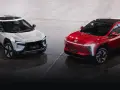Dwa futurystyczne SUV-y, biały i czerwony, marki Mahindra, prezentują nowoczesny design z ostrymi liniami i LED-owym oświetleniem.