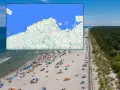 Mapa pokazuje, gdzie najcieplej nad morzem. Widać plażę pełną ludzi i parawanów.