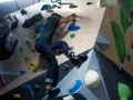Mann klettert an einer bunten Kletterwand, die aussieht, als ob sie jemand selber bauen könnte.