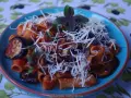 Pyszne danie pasta alla norma z makaronem rigatoni, bakłażanem w sosie pomidorowym i posypane startym serem.