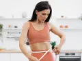 Kobieta w sportowym stroju mierzy talię, ciesząc się efektami diety low carb.