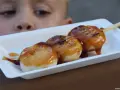 Chłopiec z zaciekawieniem patrzy na słodkie japońskie przysmaki: dango polane syropem.