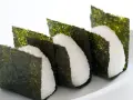 Trzy ryżowe onigiri owinięte w arkusze nori. Prosty sposób, jak przygotować nori do sushi, by nadać mu chrupkość i smak.