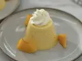 Postre de melocotón en almíbar con crema batida y trozos de melocotón.