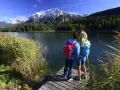 Ein Paar genießt die Aussicht auf die Berge bei Garmisch-Partenkirchen. Sie stehen auf einem Steg am See, bereit zum Wandern.