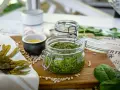 Frisches Pesto aus essbaren Algen der Nordsee, daneben Sonnenblumenkerne, Knoblauch und ein kleines Schälchen mit Öl.