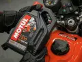 Ręce w rękawiczkach trzymają olej Motul 7100 10W-40. Pytanie: co ile wymieniać olej w motocyklu?