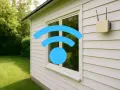 Ein WLAN-Symbol über einem Fenster und ein Router an der Hauswand signalisieren: Internet im Garten ist möglich.