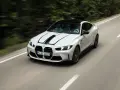 Białe BMW M4 z czarnymi pasami na masce pędzi po krętej drodze. Zastanawiasz się, ile kosztuje BMW M4?