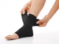 Hands adjust a black compression ankle brace, demonstrating how compression therapy works for support and recovery.