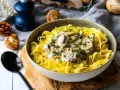 Un plat de pâtes tagliatelles garni d'une onctueuse sauce pour pâtes farcies aux champignons, parsemé de persil frais.