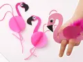 Pink paper flamingos, perfect for flamingo basteln! One is worn on a hand like a puppet, adorned with a fluffy pink feather.
