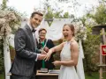 Para młoda wymienia obrączki podczas ceremonii ślubnej na zewnątrz.