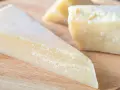 Kawałki twardego, żółtego sera na desce. Szukasz pomysłów, czym zastąpić parmezan?