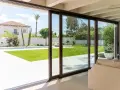 Amplias puertas correderas de cristal conectan el interior con un jardín con piscina, permitiendo una ventilación natural y la entrada de luz.