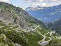 Strada tortuosa che sale sul passo Austria, circondata da montagne verdi e rocce imponenti.