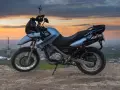 Niebieski motocykl BMW na wzgórzu, gotowy do podróży po Litwie, gdzie obowiązują ograniczenia prędkości.