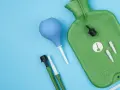 Grüne Spülflasche, blauer Birnensauger und Zubehör für die darmspiegelung vorbereitung auf blauem Hintergrund.