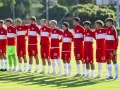 Drużyna Polski na Mistrzostwach Europy do lat 17. Piłkarze w czerwonych strojach z białymi pasami stoją w rzędzie, gotowi do meczu.