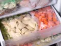 Zamrożone pierogi i warzywa w woreczkach w zamrażarce.
