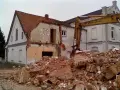 Rozbiórka budynku w granicy działki. Koparka Komatsu pracuje przy gruzach.