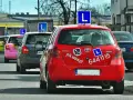 Czerwony samochód nauki jazdy z literą "L" na dachu. Zastanawiasz się, ile zarabia instruktor jazdy?