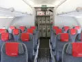 Wnętrze samolotu Air Arabia z rzędami szarych siedzeń i czerwonymi zagłówkami. W tle widać wózki pokładowe. Dobre **air arabia opinie** potwierdzają komfort podróży.