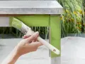 Mano pintando una mesa de madera con pintura verde brillante. El proceso de pintar con tizas da un acabado rústico y encantador.