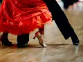 Para tańczy paso doble w rytm muzyki. Czerwona sukienka wiruje, a eleganckie buty poruszają się po parkiecie.