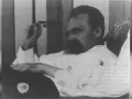 Nietzsche, zamyślony, w białej koszuli, z charakterystycznym wąsem. Jego poglądy kształtują obraz myśli.