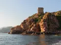 Wieża strażnicza na skalistym wybrzeżu, w oddali góry. Malownicza sceneria na corse wyspie.