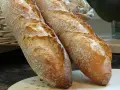 Zwei knusprige Baguettes, eine köstliche t65 Mehl Alternative, liegen auf einem Holzbrett.