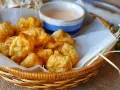 Cesta de mimbre con crujientes fritos de pixin, acompañados de una cremosa salsa rosa. ¡Un bocado delicioso!