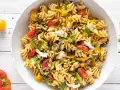 Un piatto colorato di pasta estiva veloce con fusilli, zucchine, peperoni gialli, pomodorini e mozzarella.