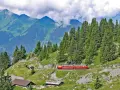 A red and yellow cogwheel train winds through the Swiss Alps, a scenic way to get around Interlaken.