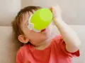 Małe dziecko pije z zielonego kubka niekapka LOVI.