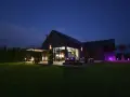 Nowoczesny dom nocą, z oświetlonym ogrodem i tarasem. Analiza prawdziwych kosztów eksploatacji domów pasywnych w polskich warunkach klimatycznych.